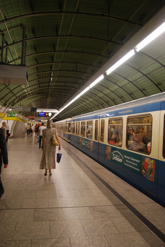 The Odeonsplatz U-Bahn station in Munich, Germany, featuring a distinctive vaulted green ceiling and a blue-and-white Munich U-Bahn train at the platform